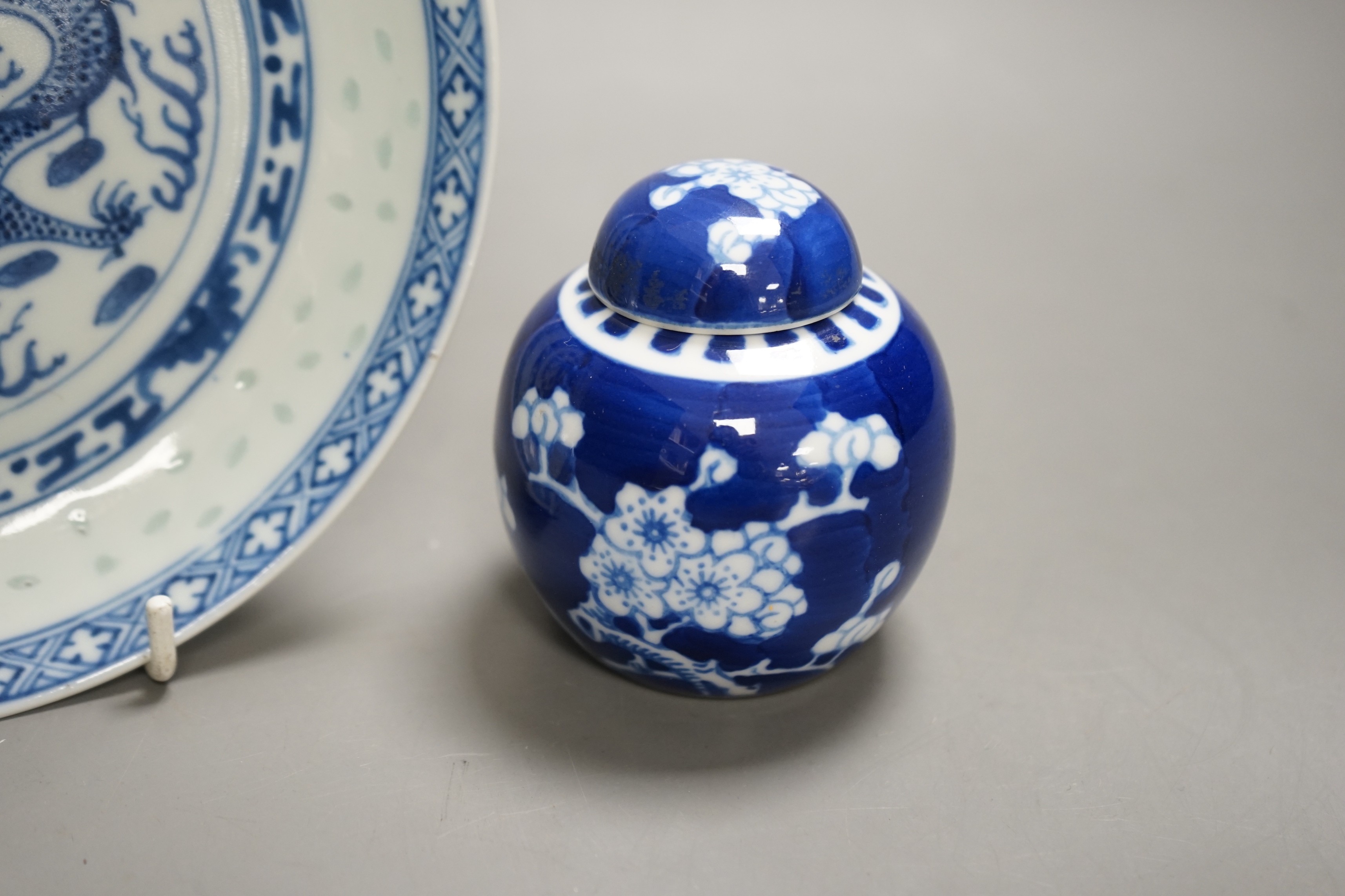 A Chinese blue and white dragon dish with rice grain border, early 20th century and a Chinese blue and white Prunus small jar and cover, dish 18cm diameter